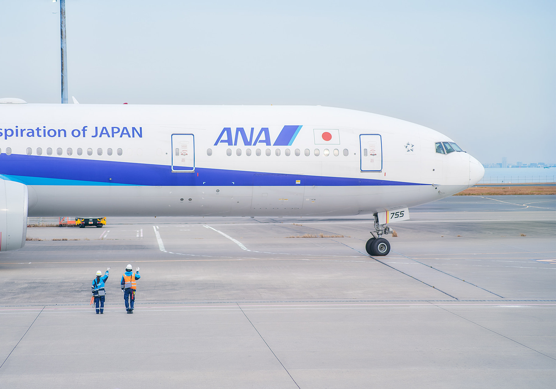 離陸するANAの飛行機に向かって手を振る二人の従業員